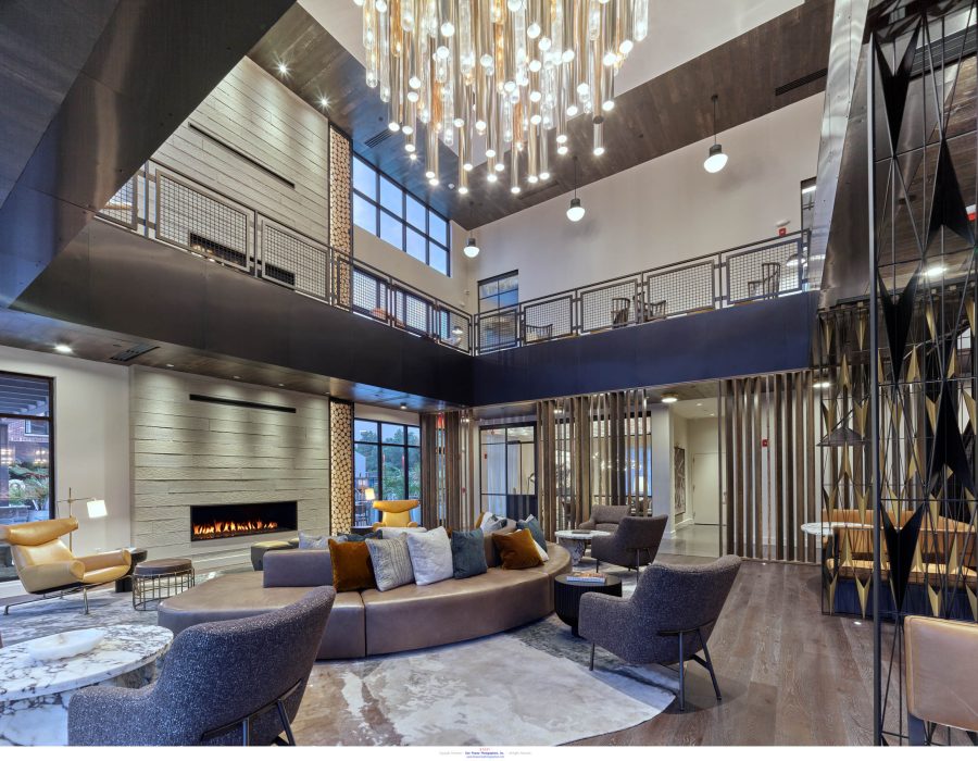 Two-story lounge with a curved leather sofa, fireplace, and a large sculptural glass pendant chandelier