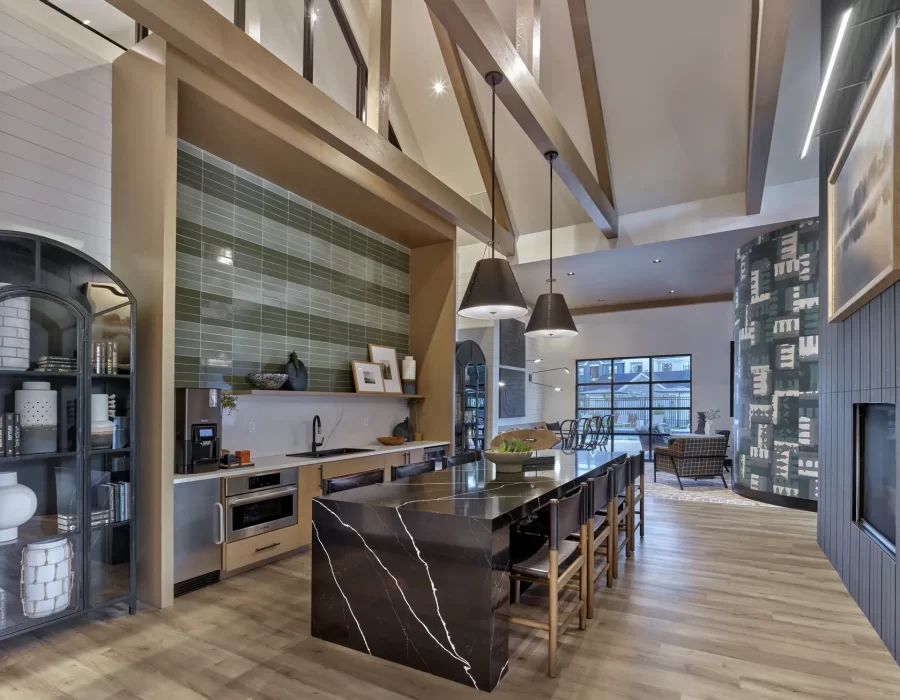 Open-concept kitchen with marble island, exposed wood beams, and vaulted ceiling leads into a living area