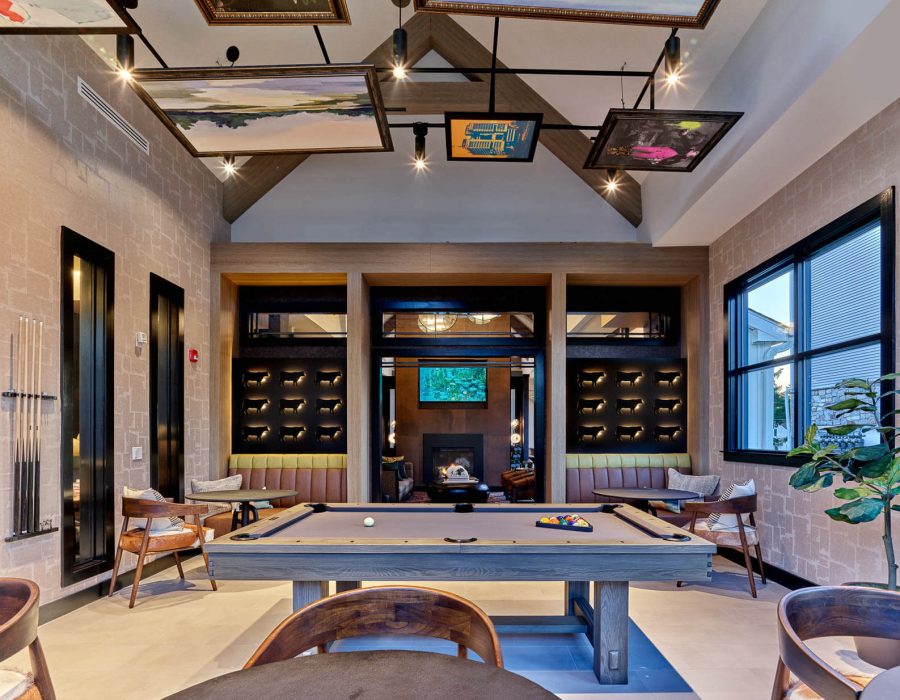 Game room with pool table, cue racks, seating booths, and a fireplace lounge visible beyond