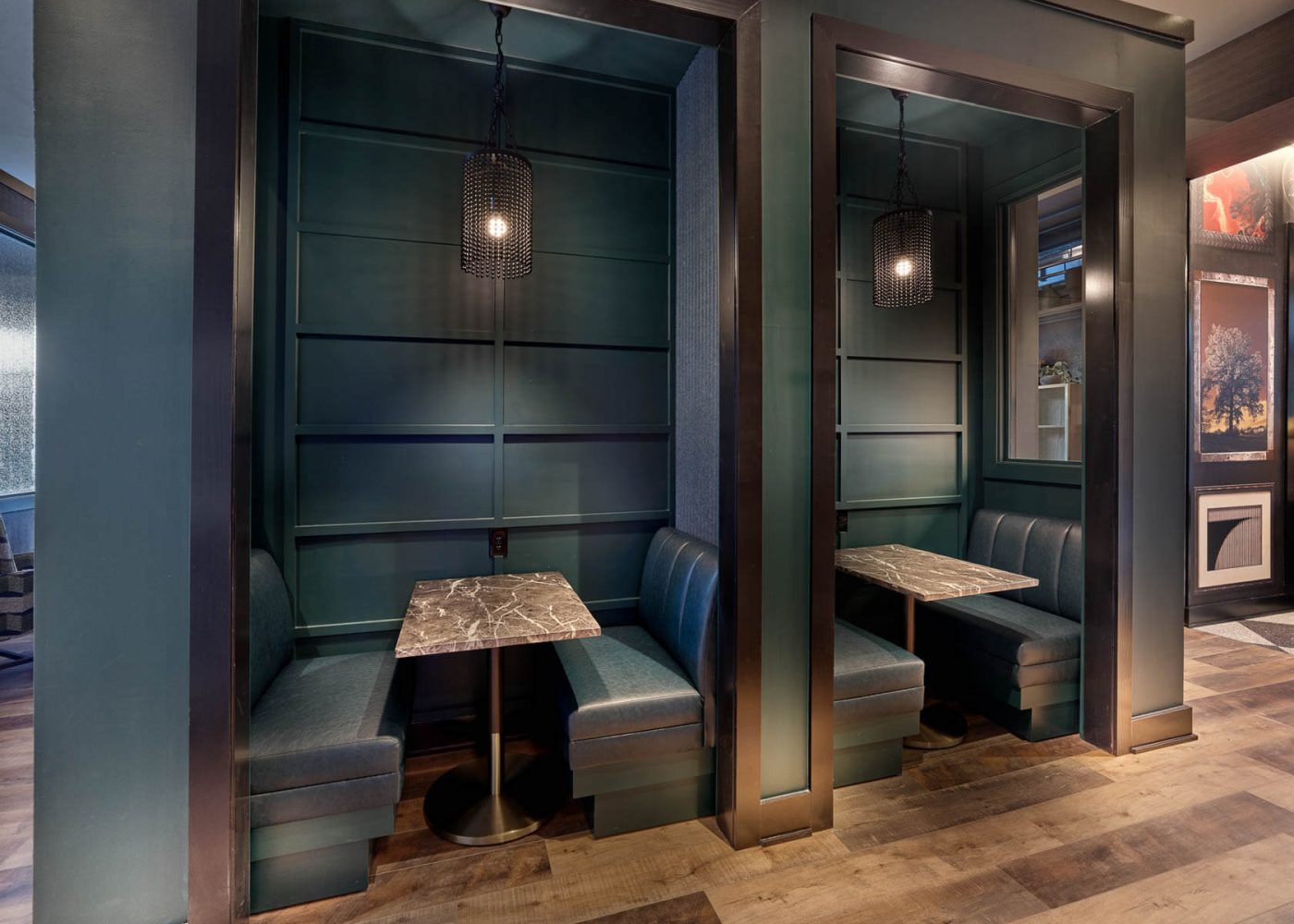 Two semi-private dining booths with navy leather seating, marble tables, and hanging pendant lights