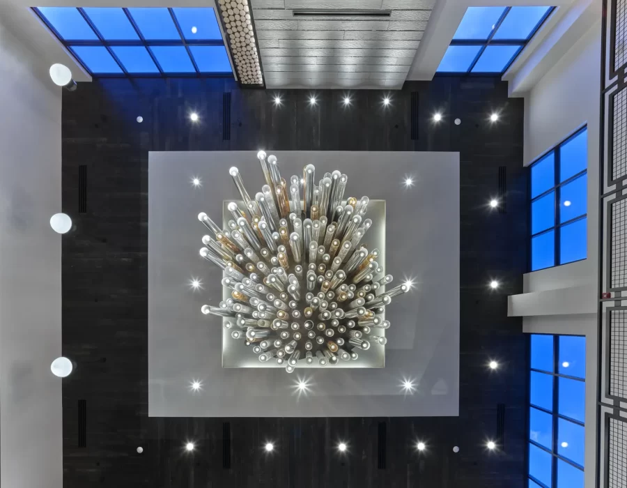 Aerial view of a starburst sculpture chandelier centered in a modern atrium with skylights and tall windows